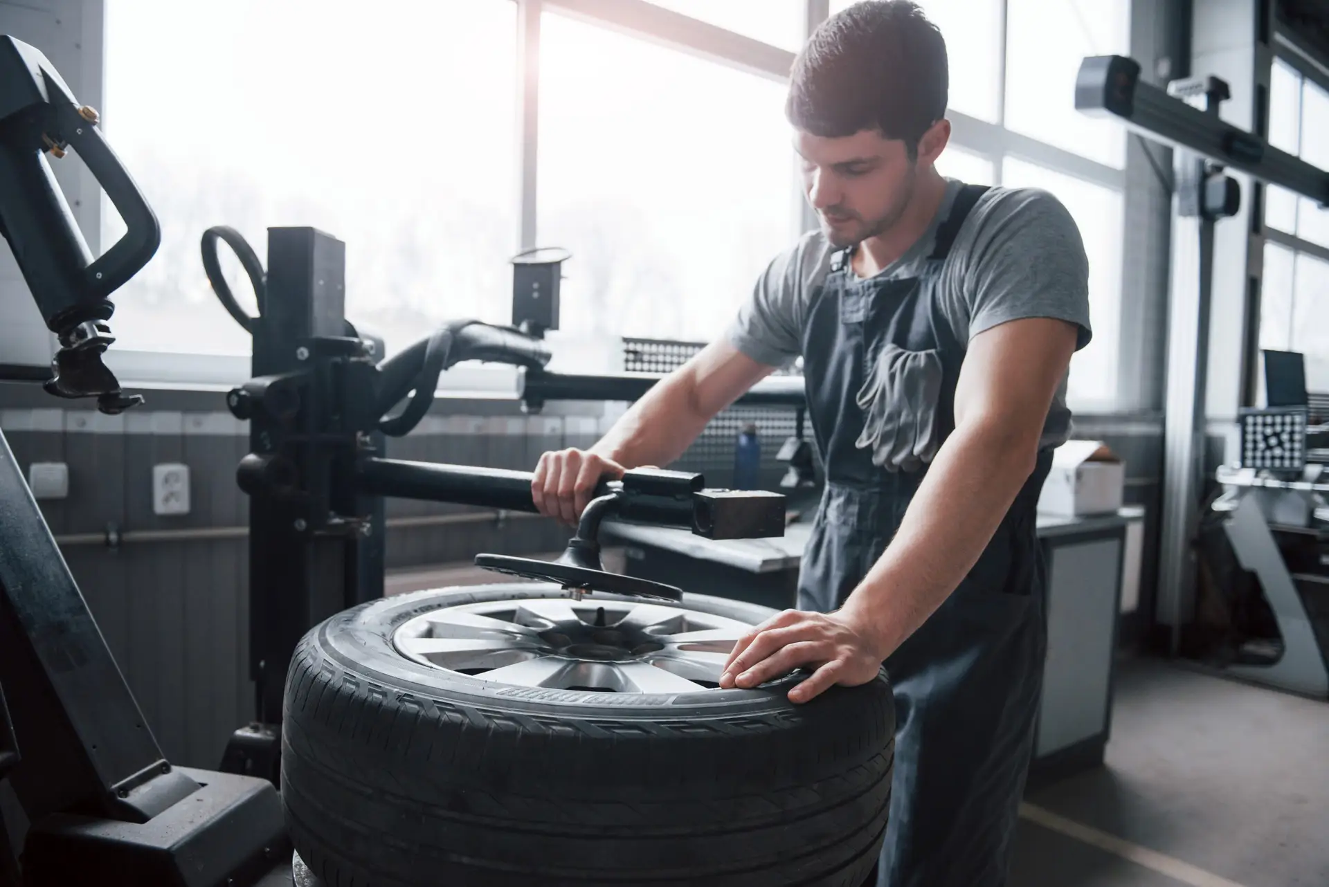 Little sunlight from the window. Young man works with wheel's disks at the workshop at daytime.