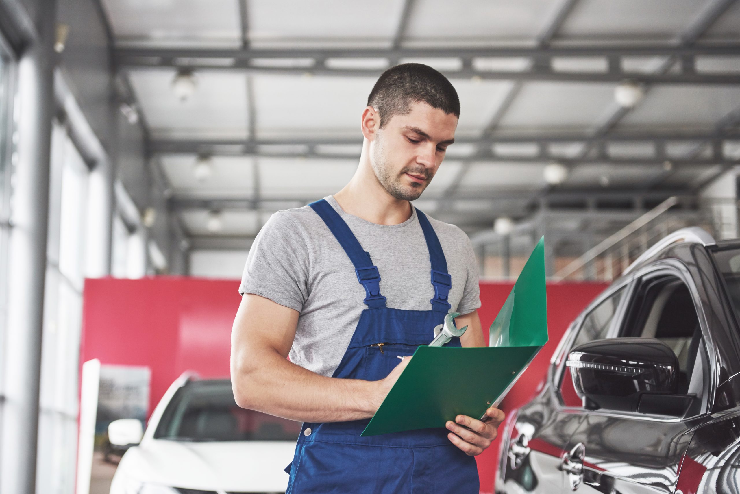 Portrait of a mechanic at work in his garage - car service, repair, maintenance and people concept.