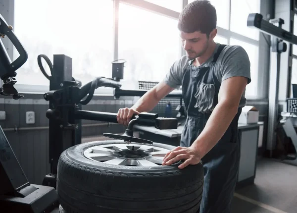 Little sunlight from the window. Young man works with wheel's disks at the workshop at daytime.