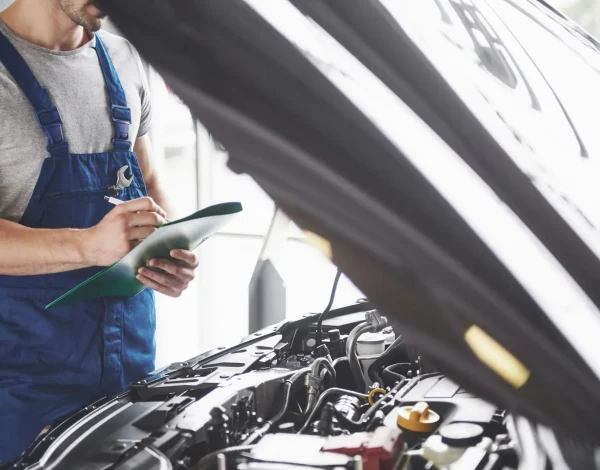 Portrait of a mechanic at work in his garage - car service, repair, maintenance and people concept.