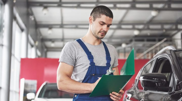 Portrait of a mechanic at work in his garage - car service, repair, maintenance and people concept.